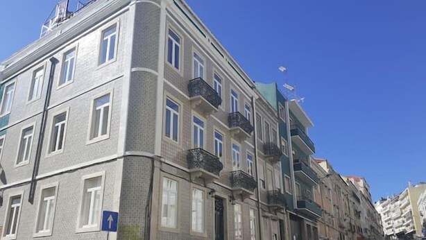 Un immeuble résidentiel à plusieurs étages, doté d’une façade sobre, de nombreux balcons et surplombant un ciel d’un bleu éclatant.