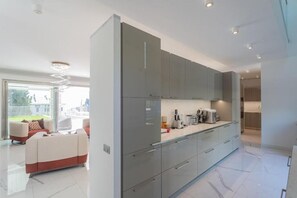 A modern kitchen with grey cabinets, a countertop with appliances, and a view to the outside. - New Villa Vogue Tremezzo (Tremezzo)