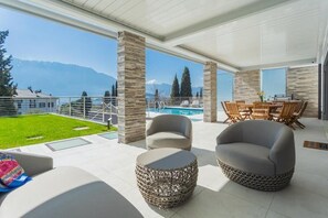 En modern uteplats med pool, sittplatser och utsikt över bergen.