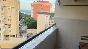 En balkon med udsigt over bybilledet, flisegulv og en stol.