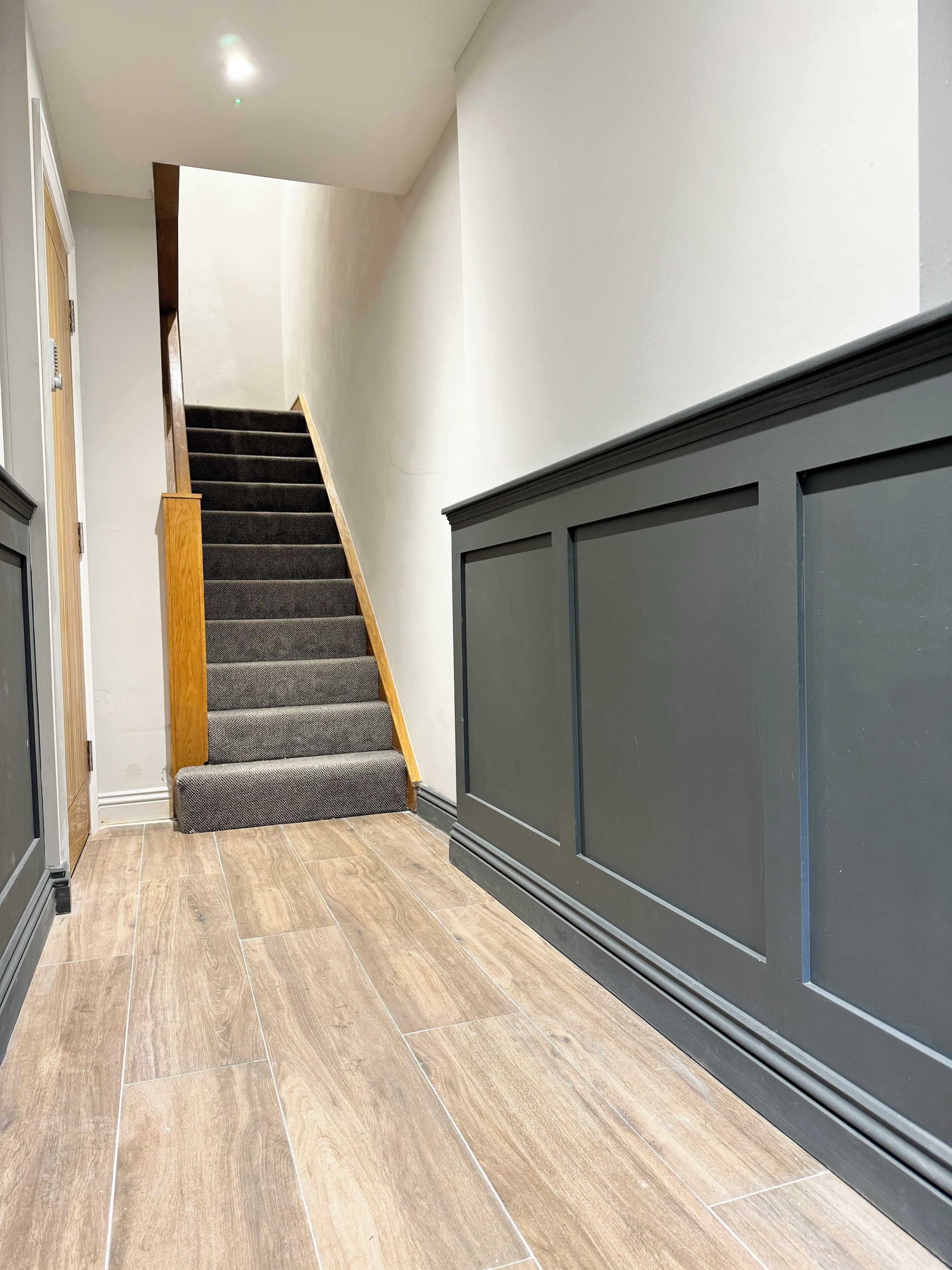 Una escalera con barandillas de madera y peldaños alfombrados que conduce a una plataforma.