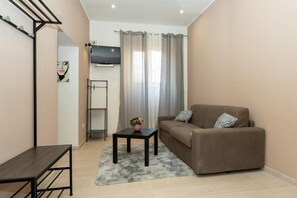 A living room with a sofa, a small table, a TV, and a window with curtains. - Catania Del Mio Cuore II (Catania)