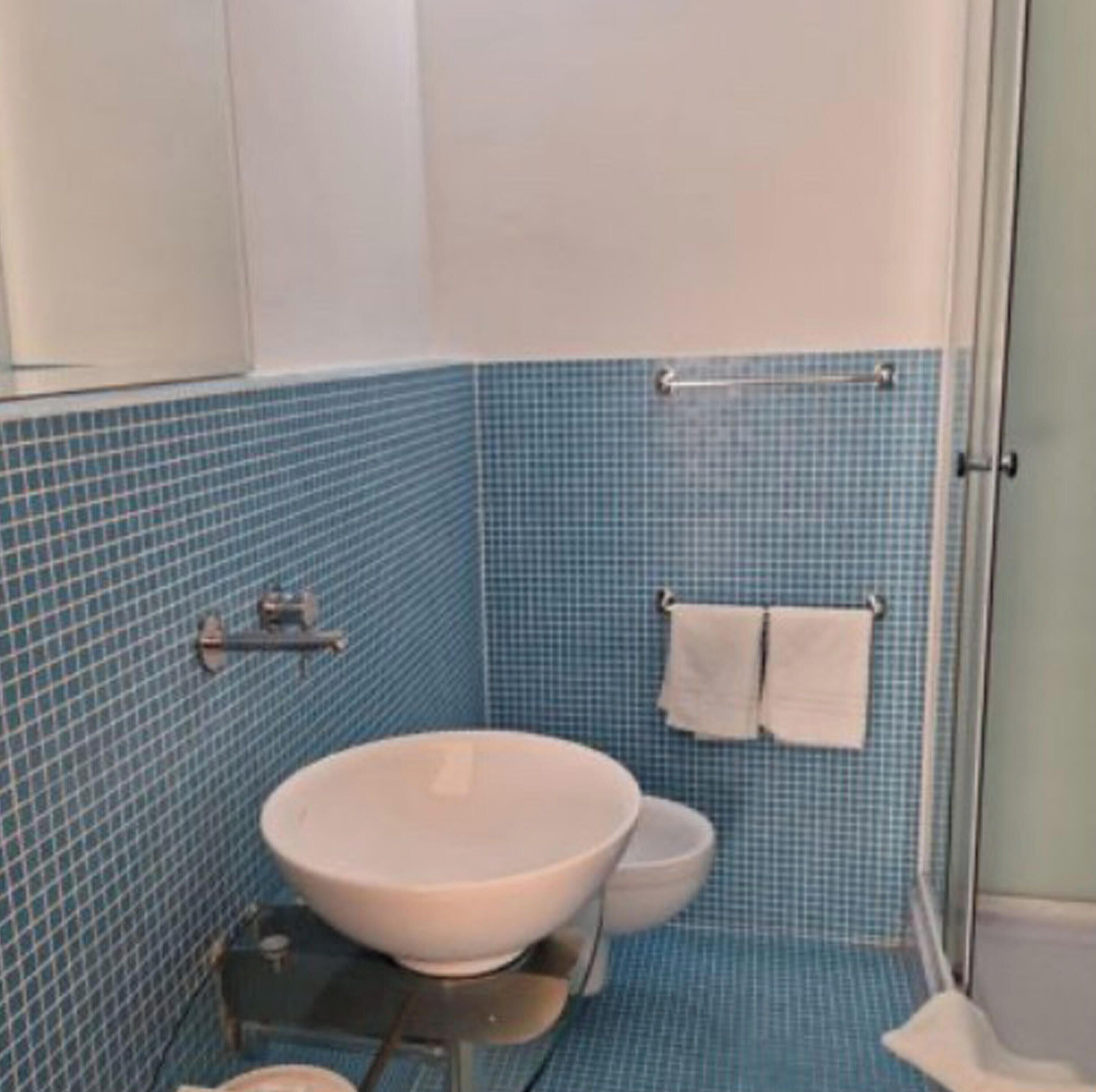 Un baño con lavamanos blanco, inodoro y zona de ducha.