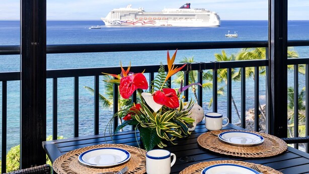 A table set for two with a view of the ocean and a cruise ship in the distance. - Ocean Front - Fantastic Location - Walk To Kona Town - Vrkcv (Kailua-Kona)