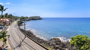 A coastal road with a view of the ocean and a hotel building in the background. - Ocean Front - Fantastic Location - Walk To Kona Town - Vrkcv (Kailua-Kona)