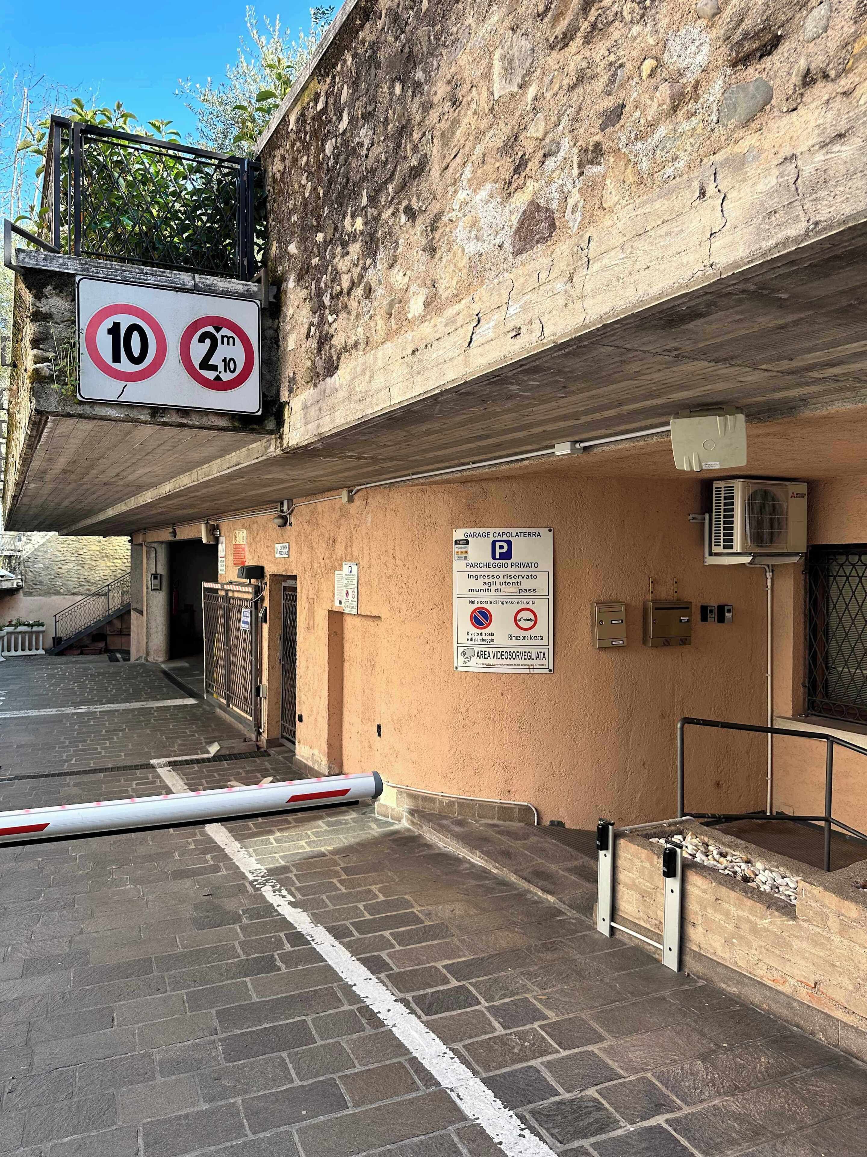 Entrada de un estacionamiento con señal de límite de velocidad, letrero de estacionamiento privado y zona de prohibido estacionar.
