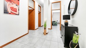 Un pasillo con diseño moderno, que incluye un espejo grande, un mueble negro con una lámpara y una obra de arte enmarcada en la pared.