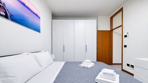 Una habitación de hotel con cama, armario, puerta de madera y un cuadro en la pared.