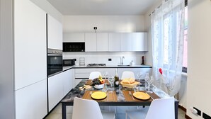 Una cocina moderna con armarios blancos, una estufa a gas y una zona de comedor con una mesa de mármol.