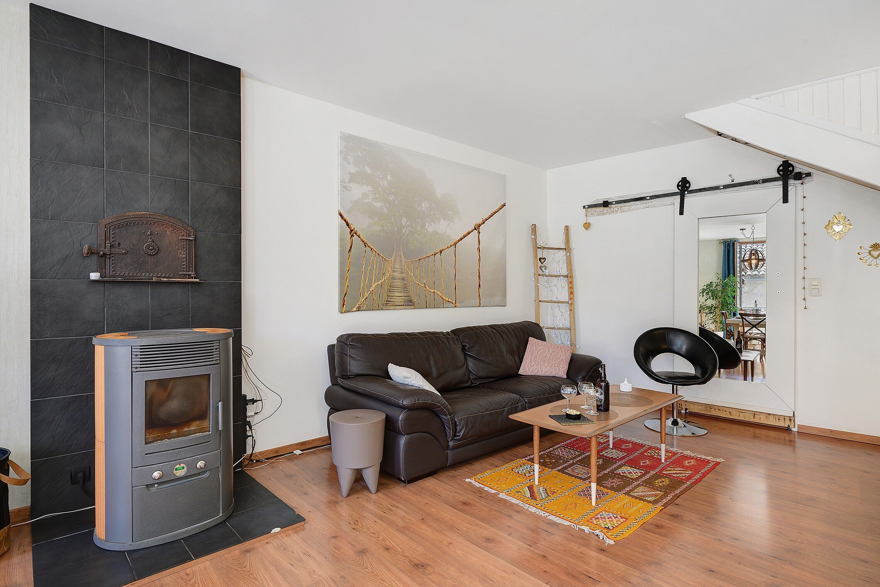 A modern living room with a fireplace, a sofa, a coffee table, and a painting of a bridge.