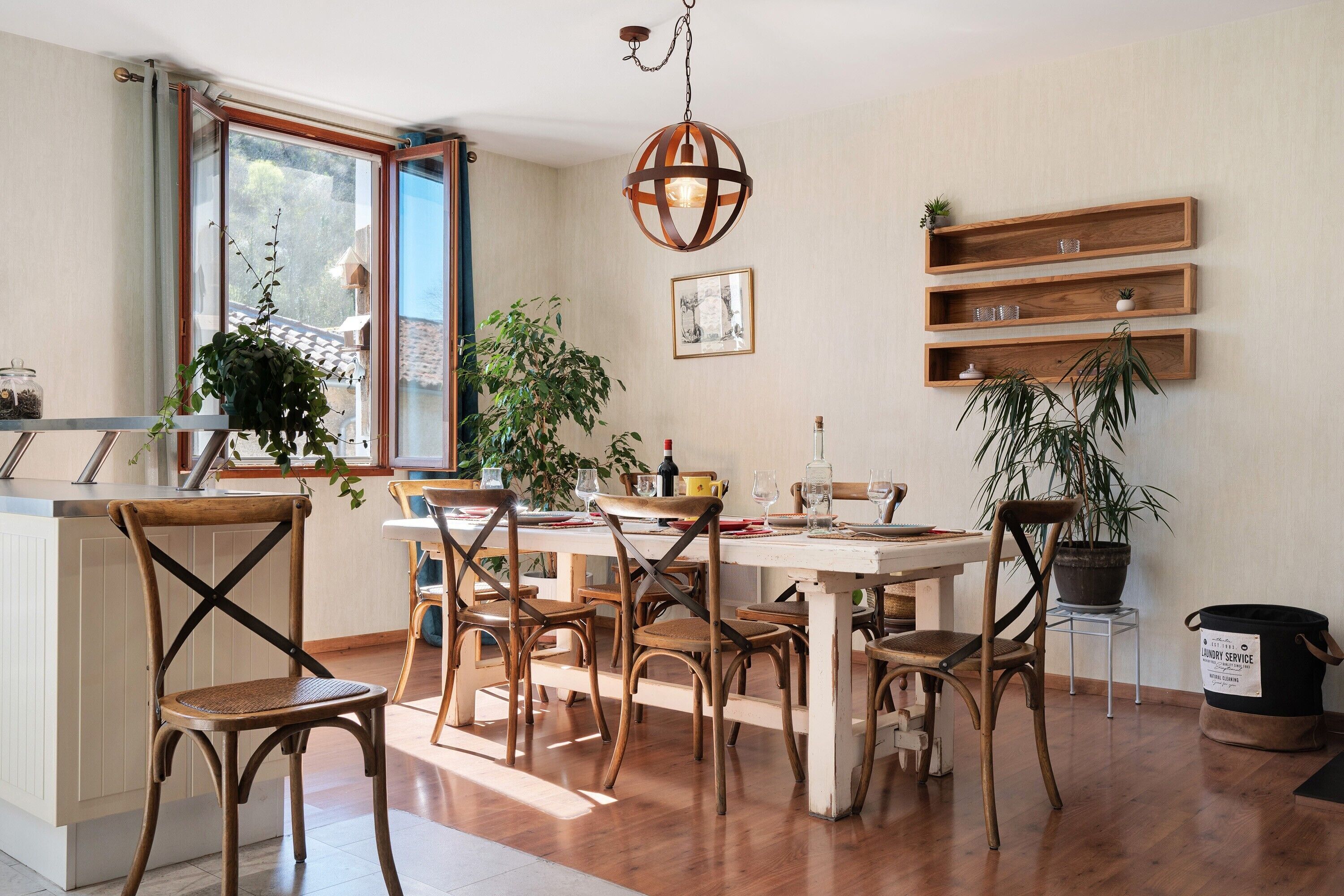 Un coin repas avec des chaises en bois, une table ronde et des plantes en pot.