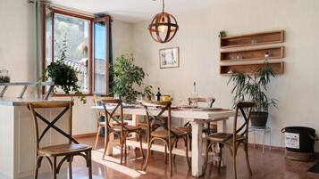 Un coin repas avec des chaises en bois, une table ronde et des plantes en pot.