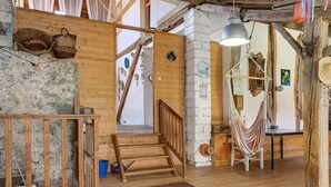 A rustic interior with wooden walls, a staircase, a hammock, and a wooden railing.