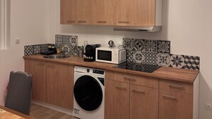 Eine moderne Küche mit Holzschränken, einer Mikrowelle, einer Kaffeemaschine und einer Waschmaschine.