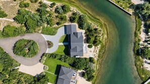 An aerial view of a property with a large house, a circular driveway, and a body of water. - Charming Waterfront Southampton Home, Perfect for Groups (Southampton)