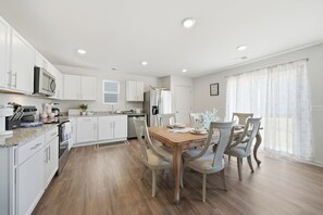 A modern kitchen with white cabinets, a wooden dining table, and chairs. - Tranquil Home in Newton (Newton)