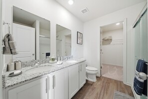 A modern bathroom with a granite countertop, white cabinets, a large mirror, and a toilet. - Tranquil Home in Newton (Newton)