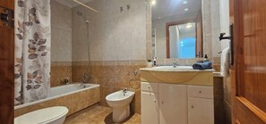 Ein Badezimmer mit Badewanne, Bidet, Waschbecken und Spiegel.