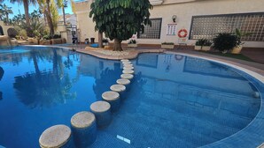 A swimming pool with a clear water path marked by circular steps, surrounded by rocks and potted plants. - Playa Marina, 4 min to the sea (Orihuela)