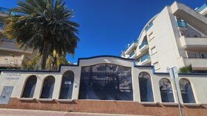 A building with a large arched entrance, multiple balconies, and a palm tree in front. - Playa Marina, 4 min to the sea (Orihuela)