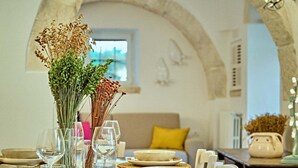 A dining table set with plates, glasses, and a vase with dried flowers. - Trullo Magia (Ostuni)