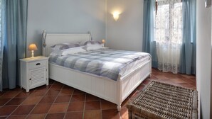 A bedroom with a bed, nightstands, a lamp, and a wicker chair. - Apartment for 6 people (RIVOLI VERONESE)