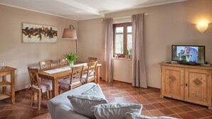 A cozy living room with a sofa, a dining table with chairs, a TV, and a window with curtains. - Apartment for 6 people (RIVOLI VERONESE)