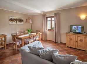 A cozy living room with a sofa, a dining table with chairs, a TV, and a window with curtains. - Apartment for 6 people (RIVOLI VERONESE)