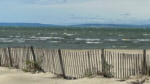 A beach with a wooden fence and waves. - Marina Giulina harbor view with jetty (Le Grau-du-Roi)