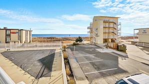 Ett hotell vid stranden med en parkeringsplats, utsikt över stranden och en byggnad med balkonger.