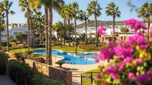 A resort with a swimming pool, palm trees, and a view of the surrounding area. - Casa d'Oro neart Vistabella Golf (Orihuela)