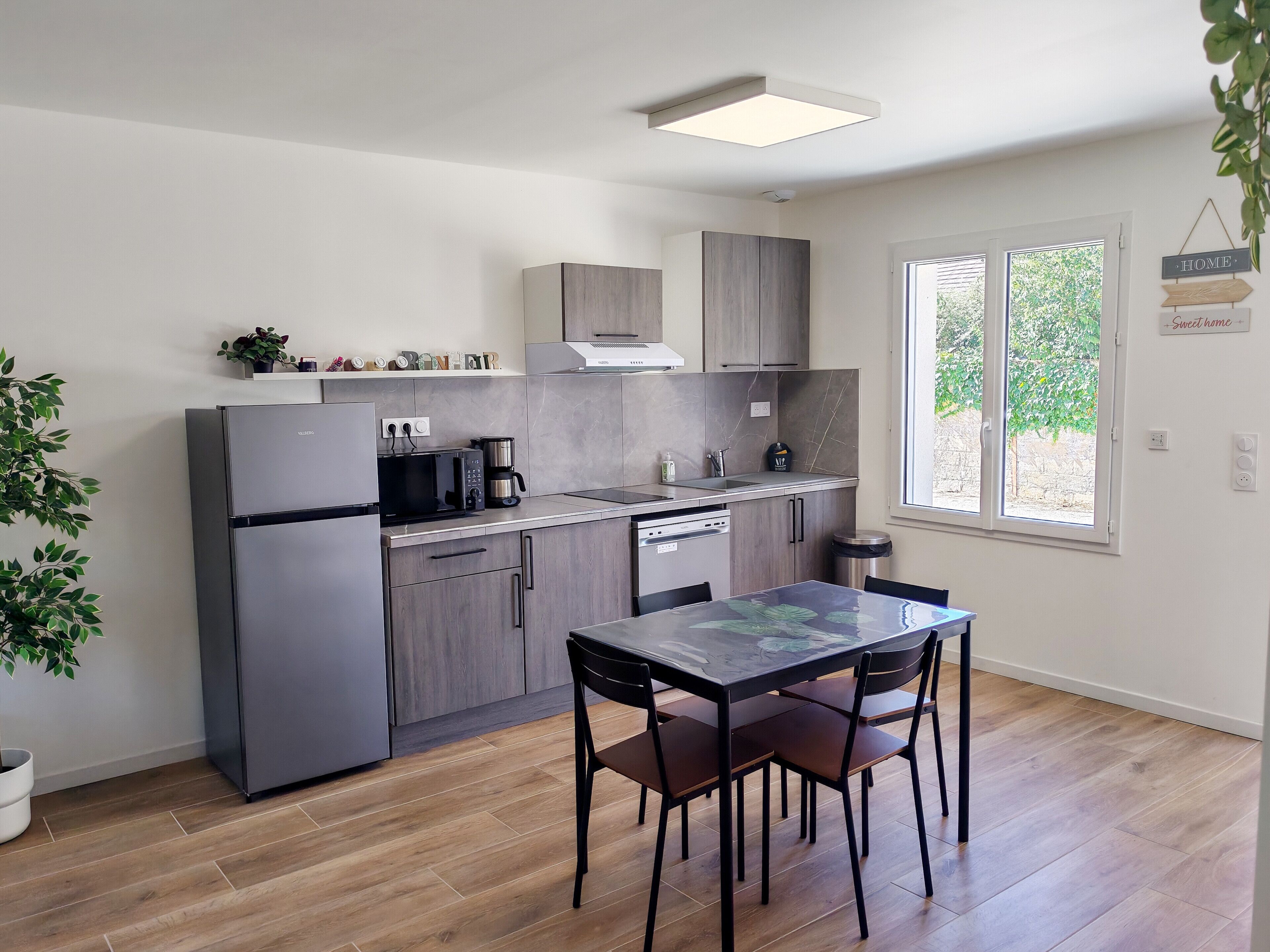 Une cuisine moderne équipée d’un réfrigérateur, d’un four à micro-ondes, d’une machine à café et d’une table à manger avec des chaises.