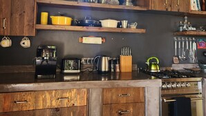 A kitchen with wooden cabinets, a gas stove, and various kitchen appliances. - Private home with exquisite mountain views in Cape Winelands (Cape Town)