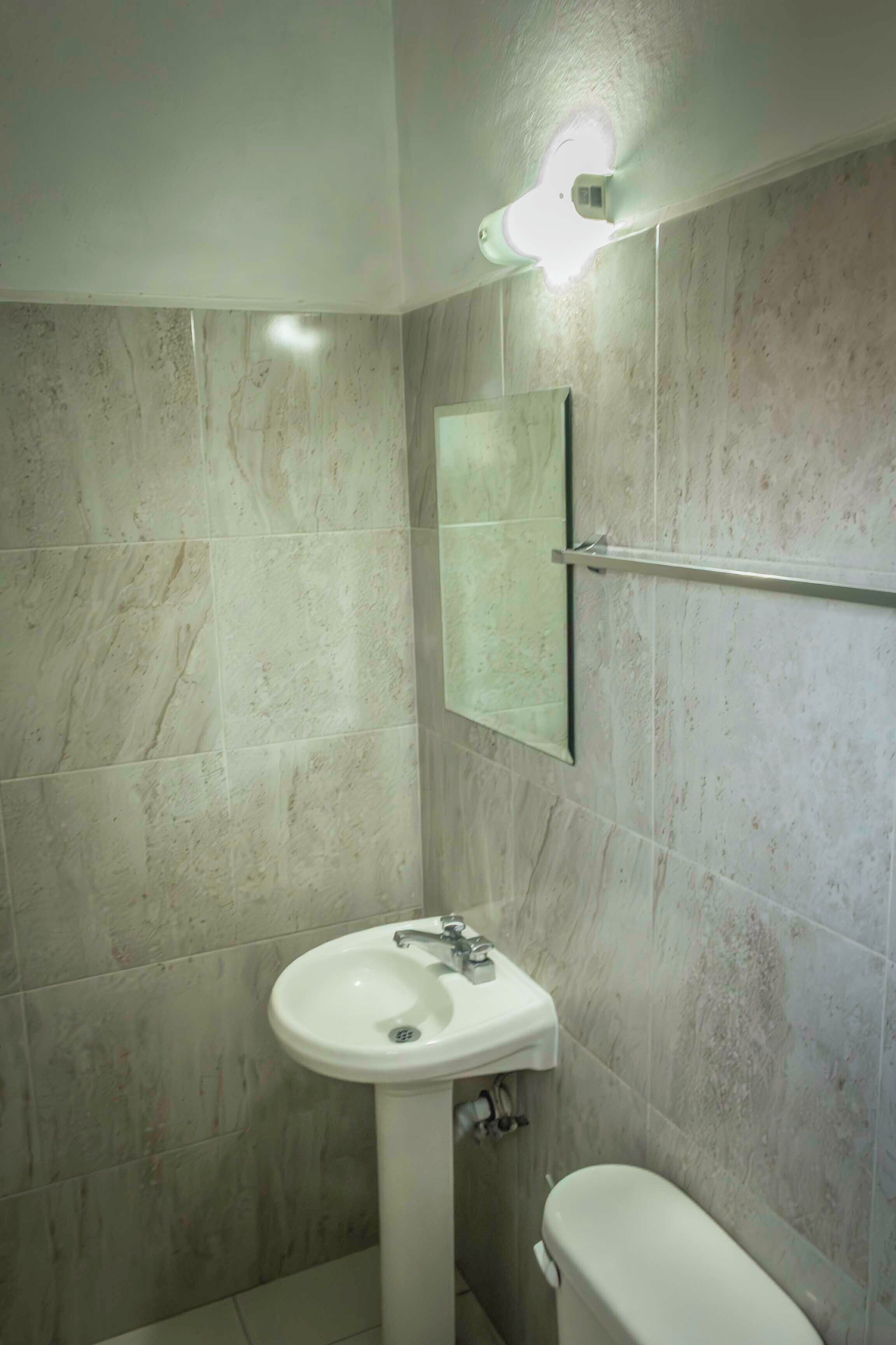 A bathroom with a white sink, a toilet, and a mirror.