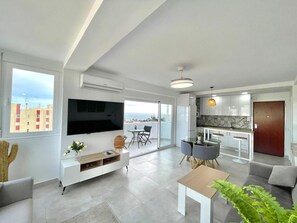 Un appartement moderne comprenant un salon, un coin repas, une cuisine et un balcon avec vue sur la ville.
