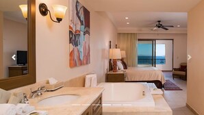 Hotelkamer met een ruime badkamer, een bed, een balkon met uitzicht en een plafondventilator.
