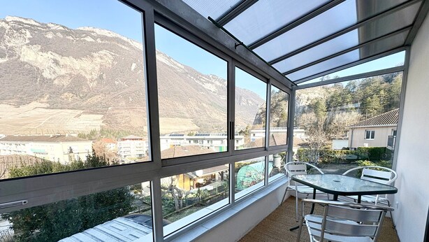 A balcony with a view of mountains, a table, and chairs. - Welcome to Montmélian, a Savoyard Town Nestled in the Heart of the Combe de Savoie! (Montmélian)
