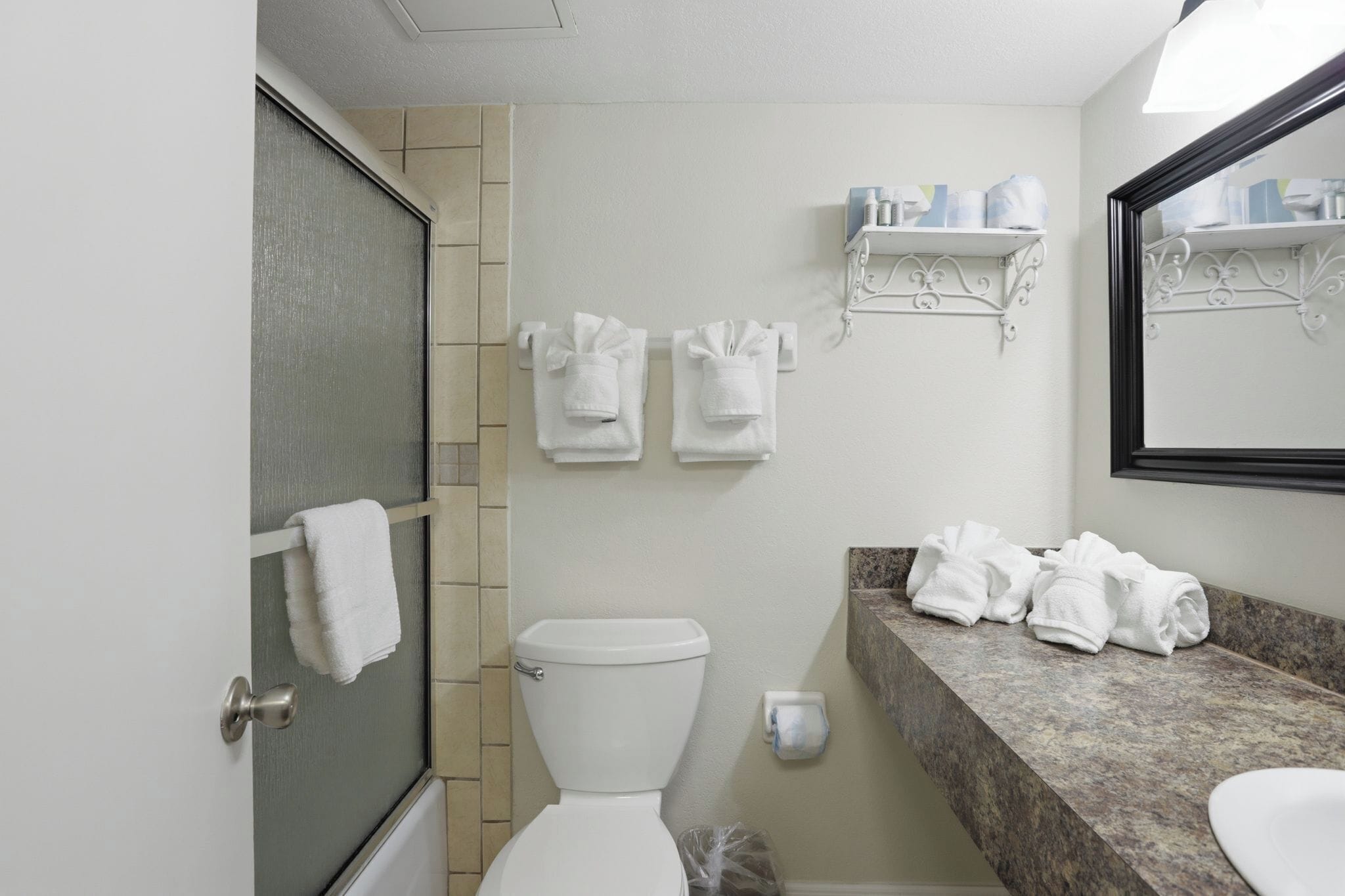 A bathroom with a toilet, a shower, a sink, and towels.