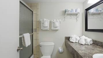 A bathroom with a toilet, a shower, a sink, and towels.