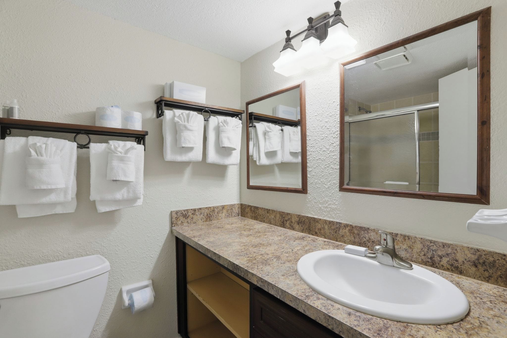A bathroom with a sink, mirror, towel rack, toilet, and shower.
