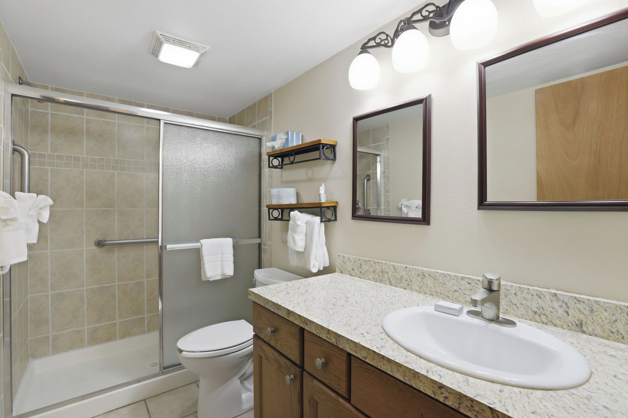 A bathroom with a shower, toilet, sink, and towel rack.