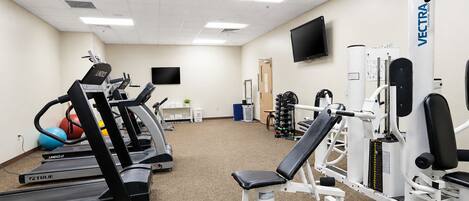 A gym with treadmills, weight machines, and a television.