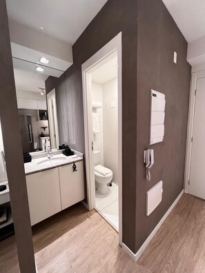 A modern bathroom with a toilet, sink, and mirror. - FACT 1208D (São Paulo)