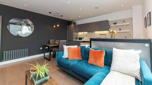 Un salon moderne avec un canapé bleu, un miroir rond et un coin repas.