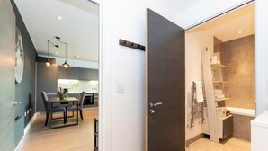 Un intérieur moderne comprenant un coin repas, une porte en bois foncé et une salle de bain avec douche et étagères.