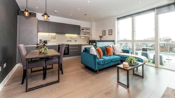 Un appartement moderne doté d’un coin repas, d’un canapé et de grandes fenêtres offrant une vue sur la ville.