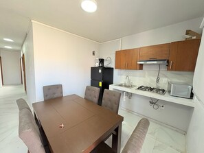 Una cocina compacta con una mesa de comedor, sillas, un refrigerador, estufa y microondas.