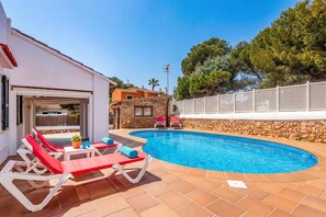 Ein privater Poolbereich mit Liegestühlen, einer Steinmauer und einem weißen Zaun.