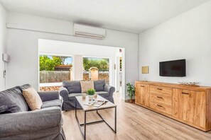 Ein modernes Wohnzimmer mit einer Couch, einem Couchtisch, einem Fernseher und einer Holzkommode.