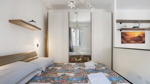 Ein Hotelzimmer mit Bett, einer Hängelampe, einem Spiegel und einem gerahmten Bild an der Wand.